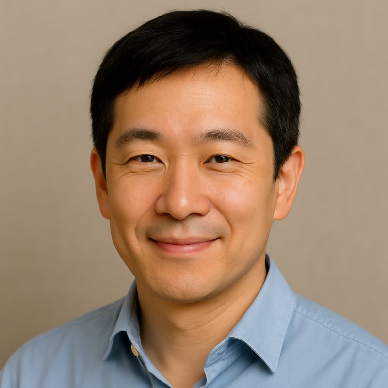 Portrait of a smiling East Asian man in a light blue shirt with short black hair